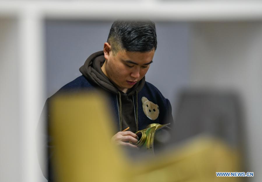Zeng Zhou views props of a Sanxingdui-themed stage play at a cultural industrial park in Chengdu, southwest China's Sichuan Province, Feb. 4, 2021. Zeng Zhou is a 31-year-old independent designer working on toy figure design. Inspired by a visiting experience at Sanxingdui Museum in Sichuan, Zeng decided to design model figures imitating bronze relics of the Sanxingdui Ruins, which are believed to be remnants of the Shu Kingdom dating back 2,600 years to 4,800 years, blending traditional Chinese culture with fashion toys. Zeng Zhou is now dedicated to optimizing his design and promoting mass production of his toy figures. 