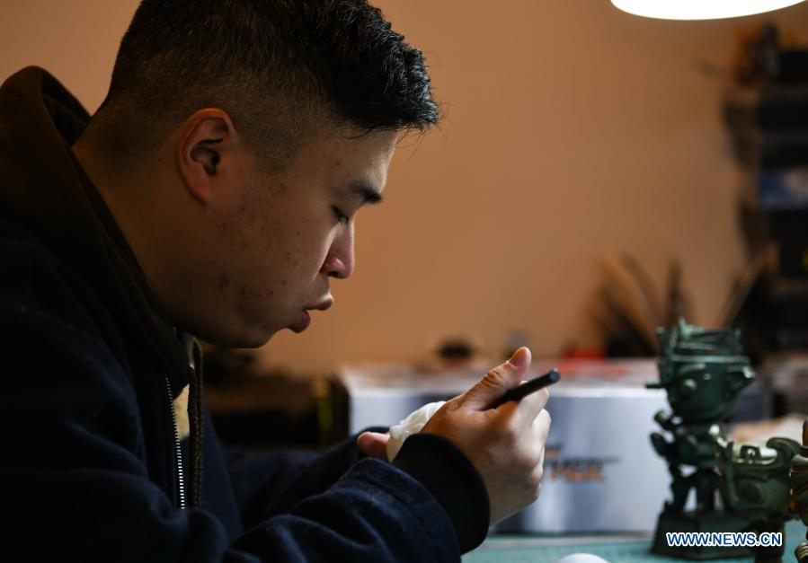 Zeng Zhou cleans a toy figure at his workshop in Chengdu, southwest China's Sichuan Province, Feb. 4, 2021. Zeng Zhou is a 31-year-old independent designer working on toy figure design. Inspired by a visiting experience at Sanxingdui Museum in Sichuan, Zeng decided to design model figures imitating bronze relics of the Sanxingdui Ruins, which are believed to be remnants of the Shu Kingdom dating back 2,600 years to 4,800 years, blending traditional Chinese culture with fashion toys. Zeng Zhou is now dedicated to optimizing his design and promoting mass production of his toy figures. 